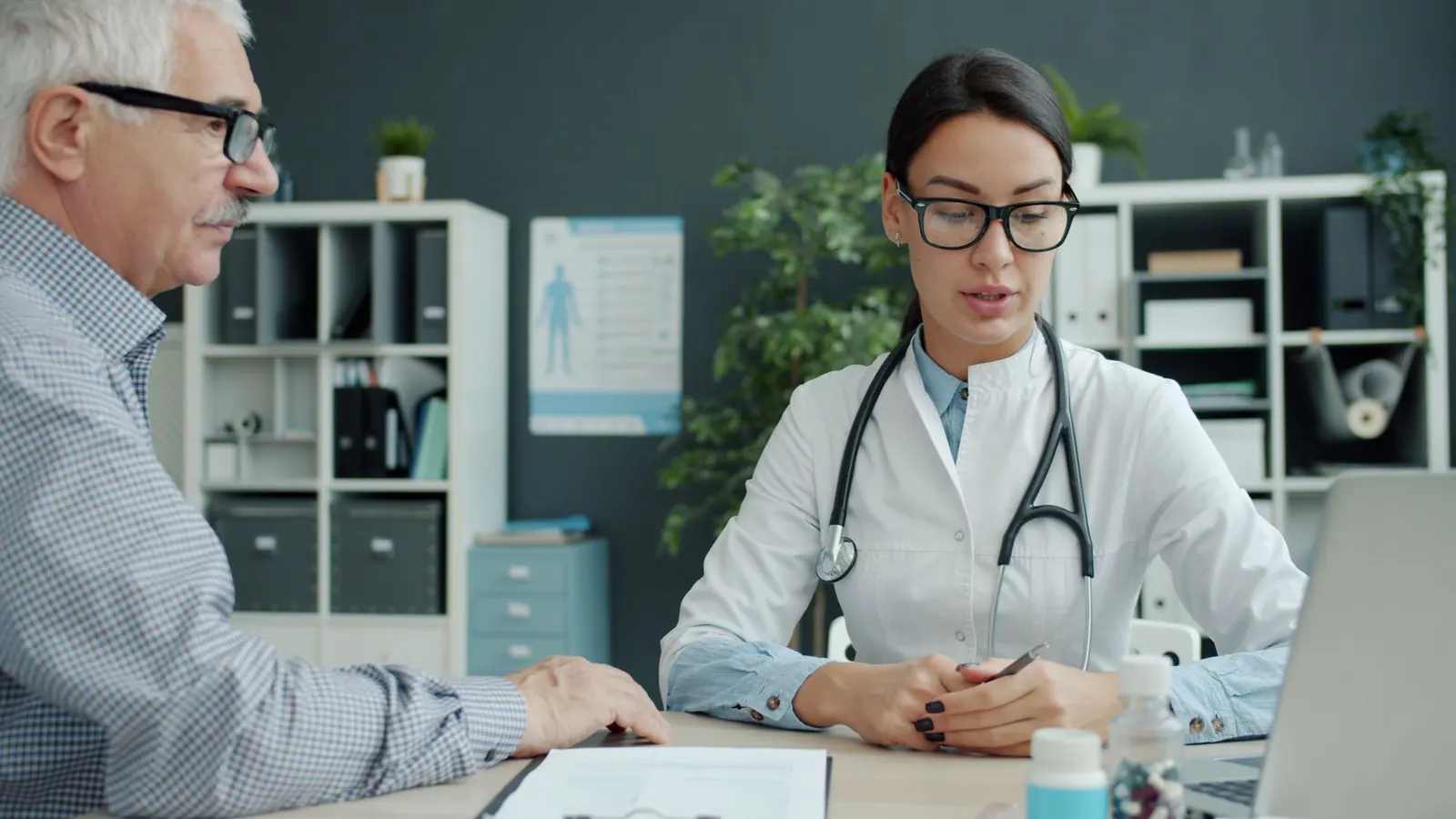 Doctor consulting an older male patient at her desk